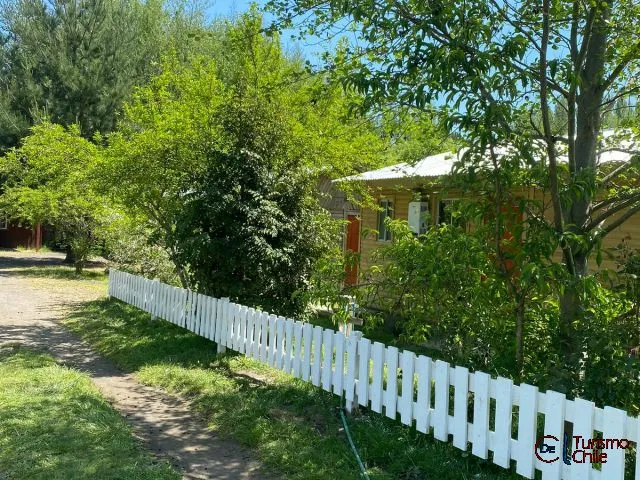 Living de cabaña con sofá de cuero, sillones y televisor